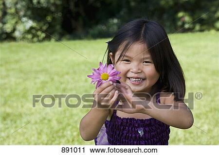 A young girl holding a flower View Large Photo Image Stock Image - A young girl holding a flower. Fotosearch