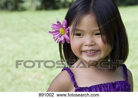A young girl with a flower behind her ear View Large Photo Image Stock Image - A young girl with a flower behind her ear. Fotosearch