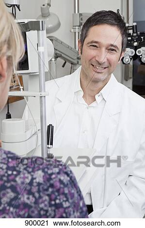Stock Image - An ophthalmologist using a slit-lamp biomicroscope to examine a patient. Fotosearch