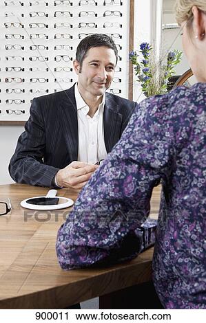 Stock Image - An optician assisting a customer in an eyewear store. Fotosearch