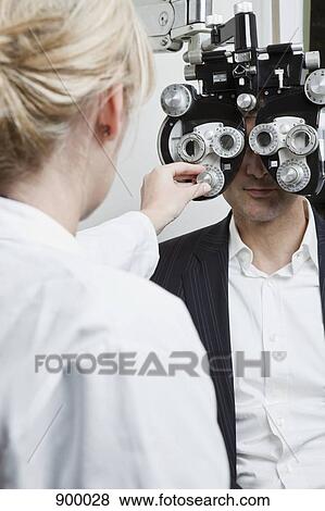 Stock Photo - An optometrist conducting an eye exam on a man. Fotosearch