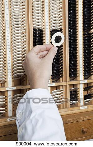 Picture - An optometrist selecting a test lens from a case. Fotosearch