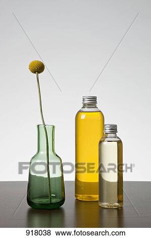 Stock Photo - Aromatherapy oil and a vase with a Billybutton Daisy (Craspedia). Fotosearch