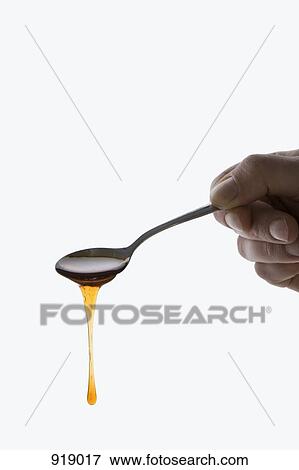 Stock Photo - Detail of a man holding a spoonful of honey. Fotosearch