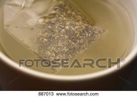 Stock Image - Detail of a teabag in a cup of water. Fotosearch