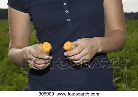 Stock Photo - Detail of a woman holding two halves of a carrot. Fotosearch