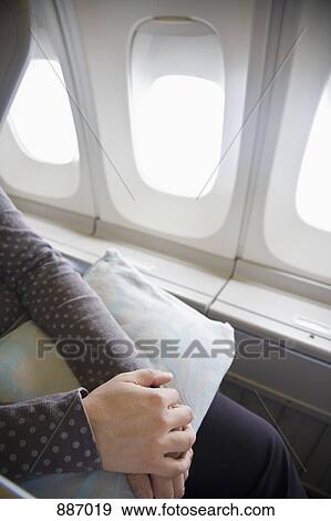 Stock Photo - Detail of a woman sitting with a cushion on a plane. Fotosearch