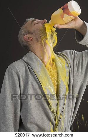 Stock Photo - Man in a bathrobe pouring orange juice into his mouth and spilling it . Fotosearch
