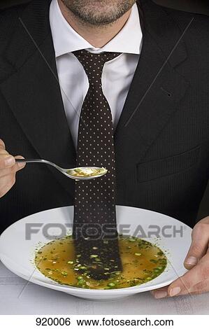 Stock Photograph - Man sitting at table with tie floating in bowl of soup. Fotosearch