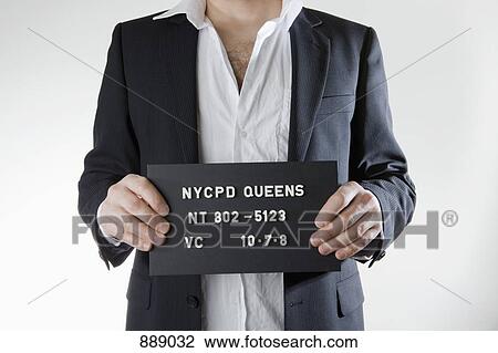 Stock Image - Midsection of a man posing for a mug shot. Fotosearch