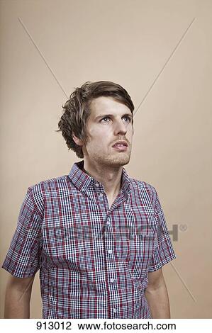 Stock Image - Portrait of a man looking up in contemplation, studio shot. Fotosearch