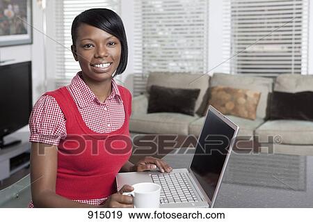 Stock Photo - Portrait of a woman sitting at a table with a laptop. Fotosearch