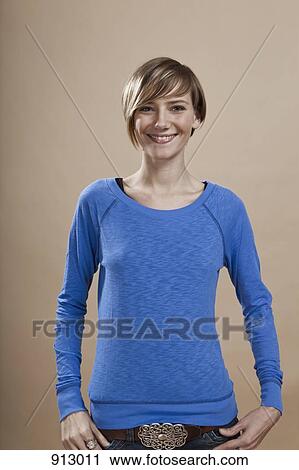 Stock Image - Portrait of a woman smiling in anticipation, studio shot. Fotosearch