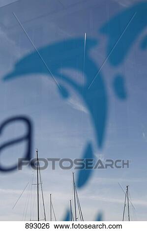 Stock Photograph - Sailboat masts in the reflection of a window with a dolphin decal. Fotosearch