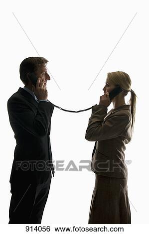 Two business people using phone receivers connected with the same cord View Large Photo Image Stock Photograph - Two business people using phone receivers connected with the same cord. Fotosearch