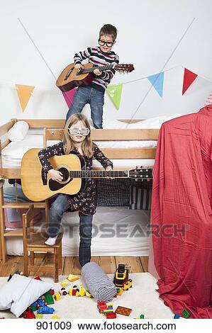 Stock Photo - Two children playing with guitars in a child's playroom. Fotosearch