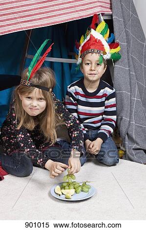Two children wearing headdresses sitting in a homemade fort View Large Photo Image Stock Photography - Two children wearing headdresses sitting in a homemade fort. Fotosearch