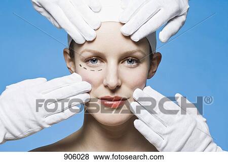 Stock Photo - Two healthcare workers, detail of hands, preparing a woman for plastic surgery, headshot. Fotosearch