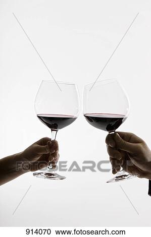 Stock Image - Two people toasting wineglasses, focus on hands. Fotosearch