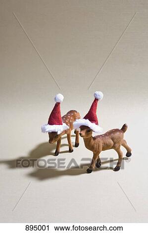 Two reindeer figurines wearing Santa hats View Large Photo Image Stock Image - Two reindeer figurines wearing Santa hats. Fotosearch