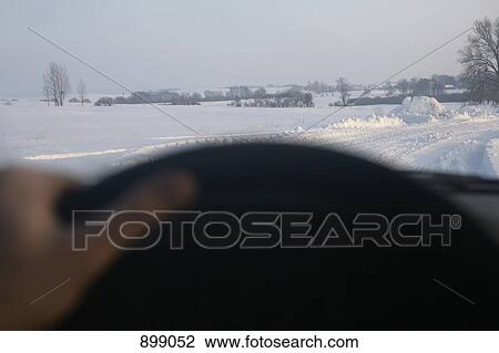 Stock Image - View of snow covered country road through car windshield. Fotosearch