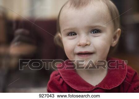 Stock Image - A baby looking through a window at the camera, portrait. Fotosearch