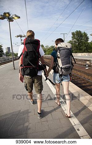 Picture - A backpacker couple walking on down a train platform. Fotosearch