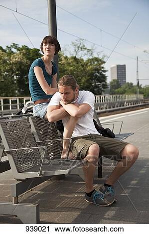 A bored backpacker couple waiting for their train on a train platform View Large Photo Image Stock Image - A bored backpacker couple waiting for their train on a train platform. Fotosearch