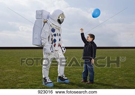 A boy holding out a balloon to an astronaut View Large Photo Image Stock Photograph - A boy holding out a balloon to an astronaut. Fotosearch
