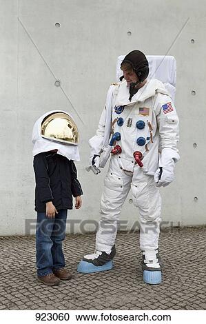 A boy in a space helmet looking up and standing next to an astronaut View Large Photo Image Stock Image - A boy in a space helmet looking up and standing next to an astronaut. Fotosearch