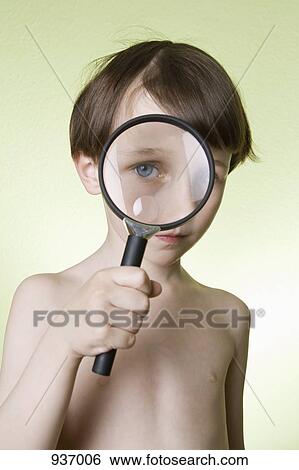 Stock Photograph - A boy looking through a magnifying glass at the camera. Fotosearch