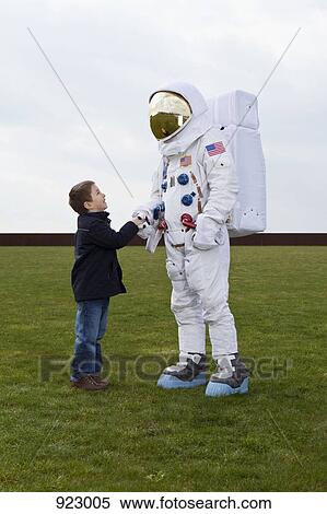 Stock Photography - A boy shaking hands with an astronaut. Fotosearch