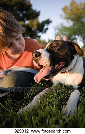 A boy sitting on grass with a dog View Large Photo Image Stock Image - A boy sitting on grass with a dog. Fotosearch