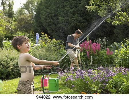 A boy squirting a hose in a garden View Large Photo Image Stock Image - A boy squirting a hose in a garden. Fotosearch