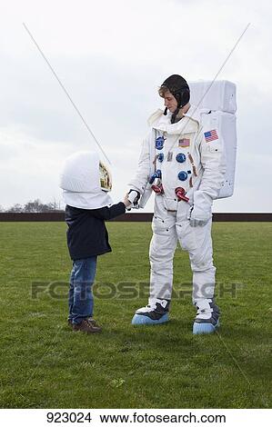 Picture - A boy wearing a space helmet shaking hands with an astronaut. Fotosearch