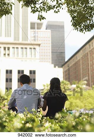 A businessman and a businesswoman sitting side by side in a downtown park, rear view View Large Photo Image Stock Image - A businessman and a businesswoman sitting side by side in a downtown park, rear view. Fotosearch