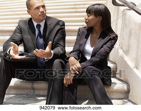 A businessman and businesswoman sitting on some stairs and having a discussion View Large Photo Image Stock Photo - A businessman and businesswoman sitting on some stairs and having a discussion. Fotosearch