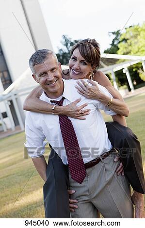 Stock Image - A businessman carrying a woman on his back. Fotosearch