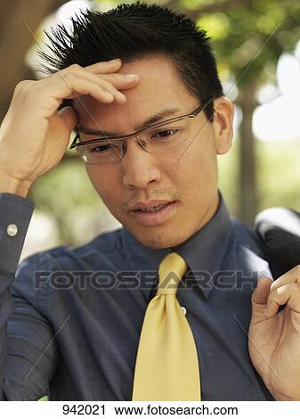 A businessman holding his forehead and grimacing View Large Photo Image Stock Image - A businessman holding his forehead and grimacing. Fotosearch