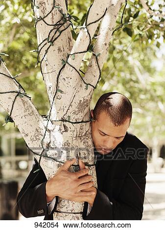 A businessman hugging a tree View Large Photo Image Picture - A businessman hugging a tree. Fotosearch