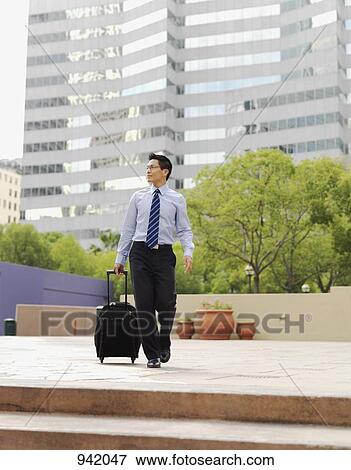 A businessman pulling a rolling suitcase View Large Photo Image Stock Photo - A businessman pulling a rolling suitcase. Fotosearch
