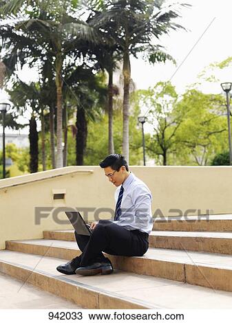 A businessman sitting cross-legged on some steps, using a laptop View Large Photo Image Stock Image - A businessman sitting cross-legged on some steps, using a laptop. Fotosearch