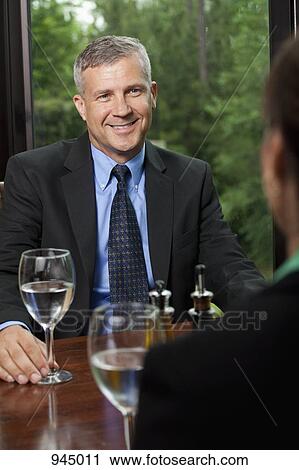 Stock Image - A businessman sitting opposite a colleague at a restaurant. Fotosearch