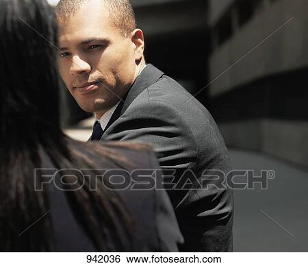 Stock Photograph - A businessman talking with a colleague, outdoors. Fotosearch