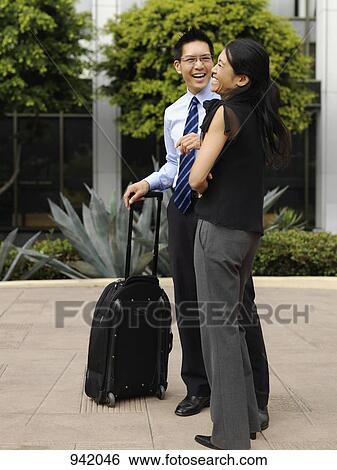 A businessman with a rolling suitcase and a businesswoman sharing a laugh View Large Photo Image Stock Photograph - A businessman with a rolling suitcase and a businesswoman sharing a laugh. Fotosearch