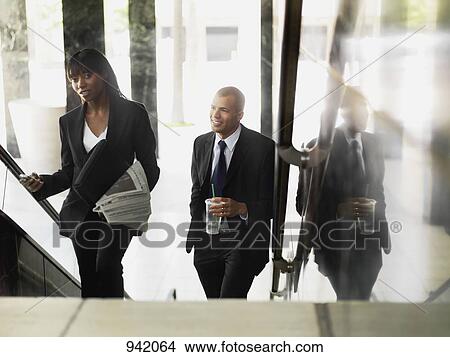 Picture - A businesswoman and businessman walking up stairs. Fotosearch