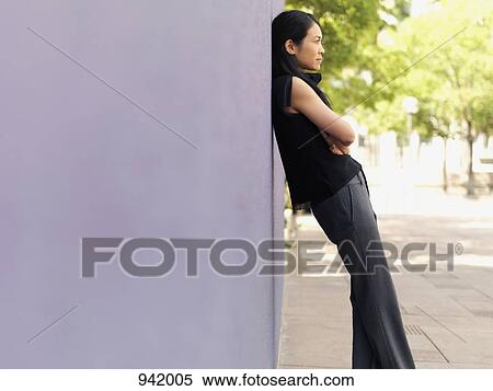 A businesswoman leaning against a wall View Large Photo Image Stock Photography - A businesswoman leaning against a wall. Fotosearch