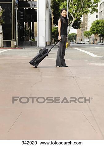 A businesswoman pulling a rolling suitcase View Large Photo Image Stock Image - A businesswoman pulling a rolling suitcase. Fotosearch