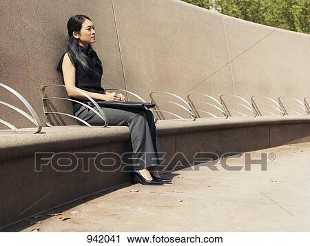 A businesswoman sitting on a cement bench View Large Photo Image Stock Image - A businesswoman sitting on a cement bench. Fotosearch