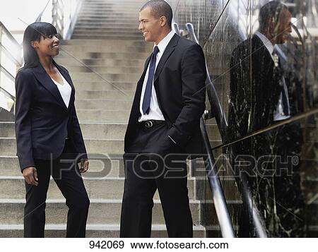 Stock Photo - A businesswoman talking with a businessman outside of an office building. Fotosearch